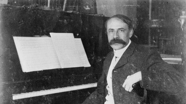 Sir Edward Elgar sitting in front of a piano